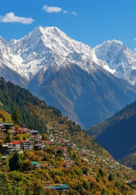 “Snow-covered Himalayan mountain peaks with a scenic valley and colorful hillside village in Himachal Pradesh”