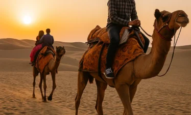 “People riding camels in the desert during sunset in Jaisalmer Rajasthan”