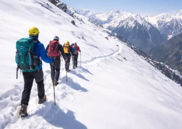 Snow trekking adventure in the Himalayas with a group of travelers hiking on a snowy mountain trail under clear blue sky