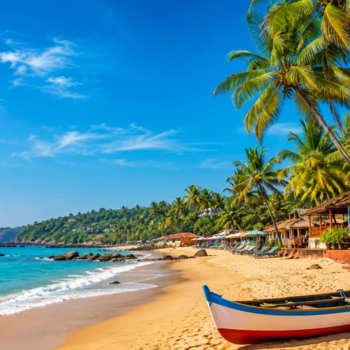 Beautiful Goa beach with palm trees, fishing boat, golden sand, beach shacks and clear blue sea under a sunny sky